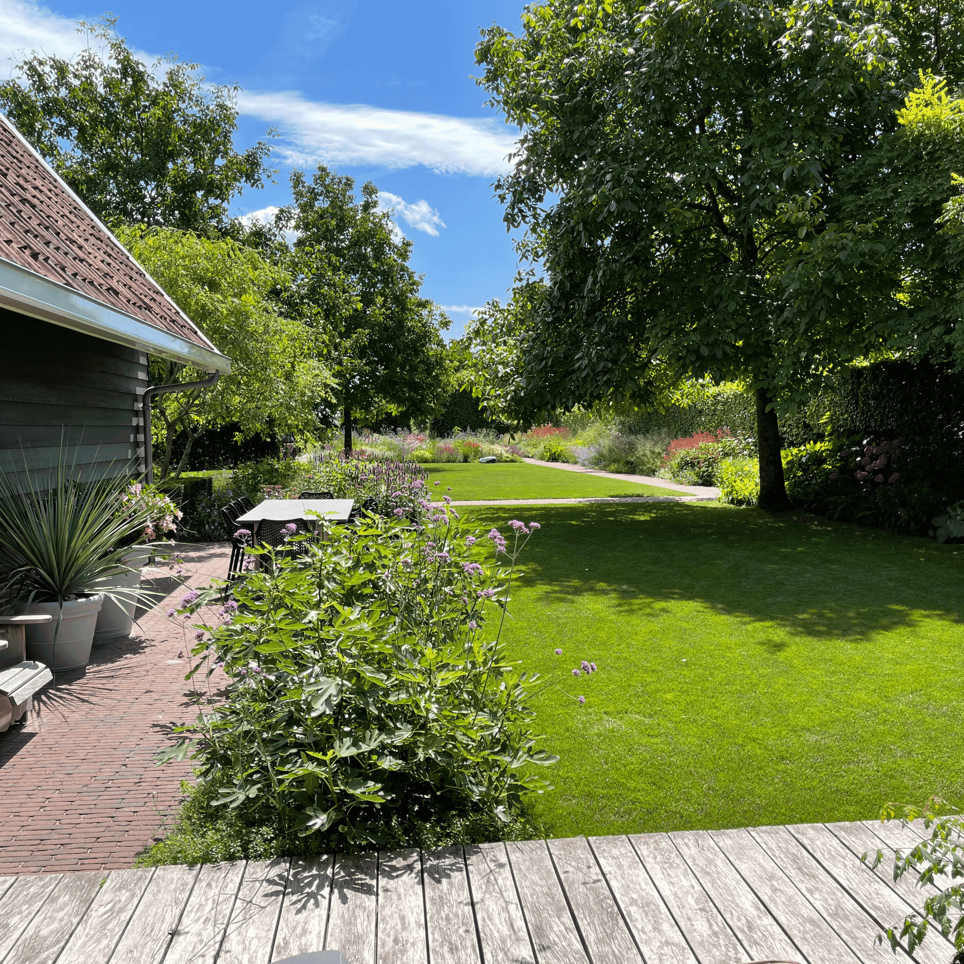Modern two-story home with large glass windows, warmly lit interiors, and a balcony. Surrounded by trees and a manicured lawn at dusk. Cozy ambiance.