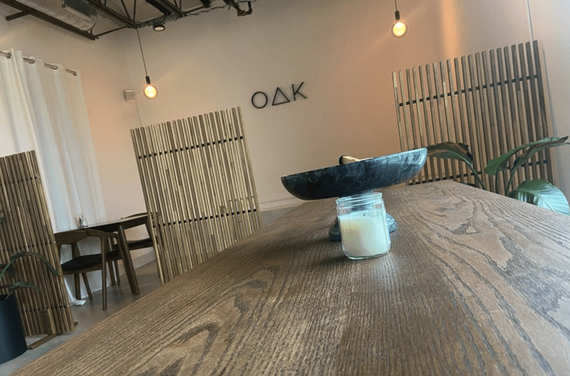 Oak & Saint café interior with wood table, sculptural centerpiece, and OAK wall logo.