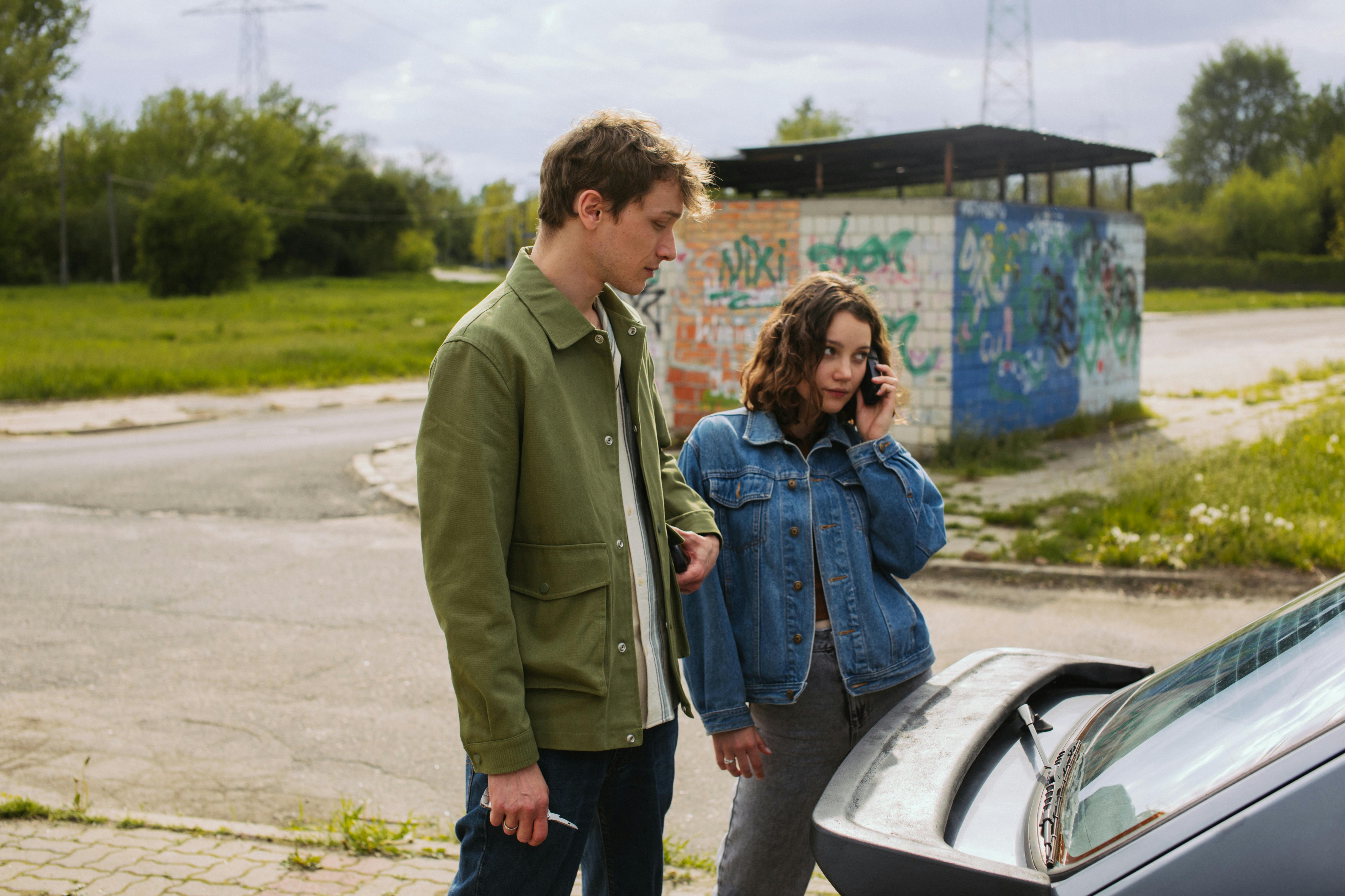 A man and woman standing next to a car