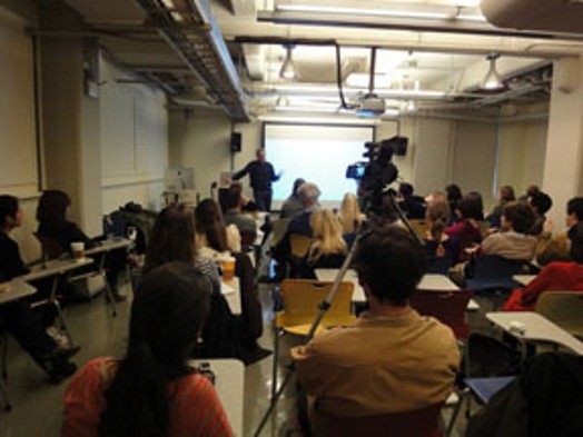 A photo of a classroom where a lecture is taking place and is being filmed.
