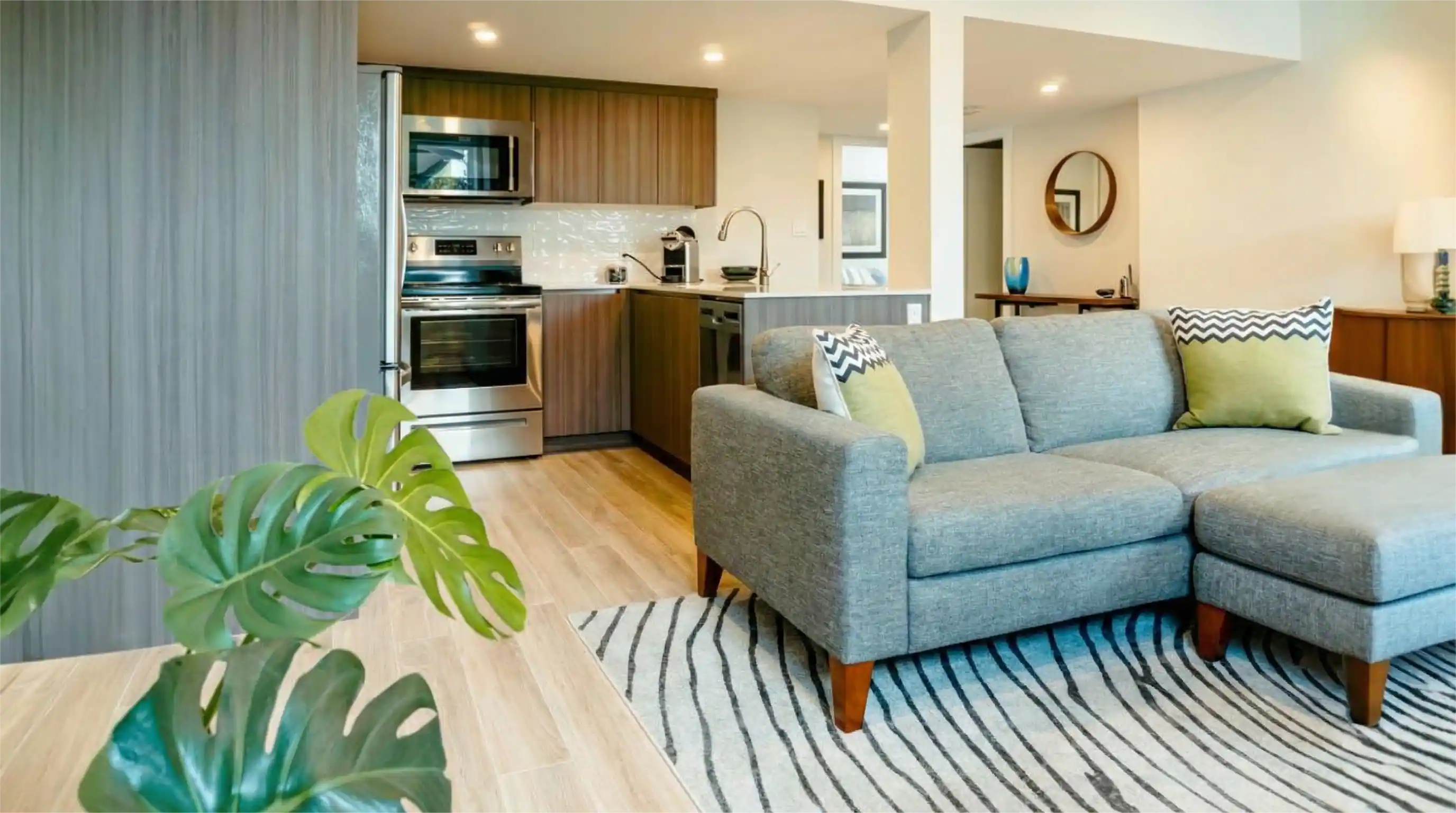 Open concept living and kitchen area with gray sectional sofa and stainless appliances in Burnaby custom residence