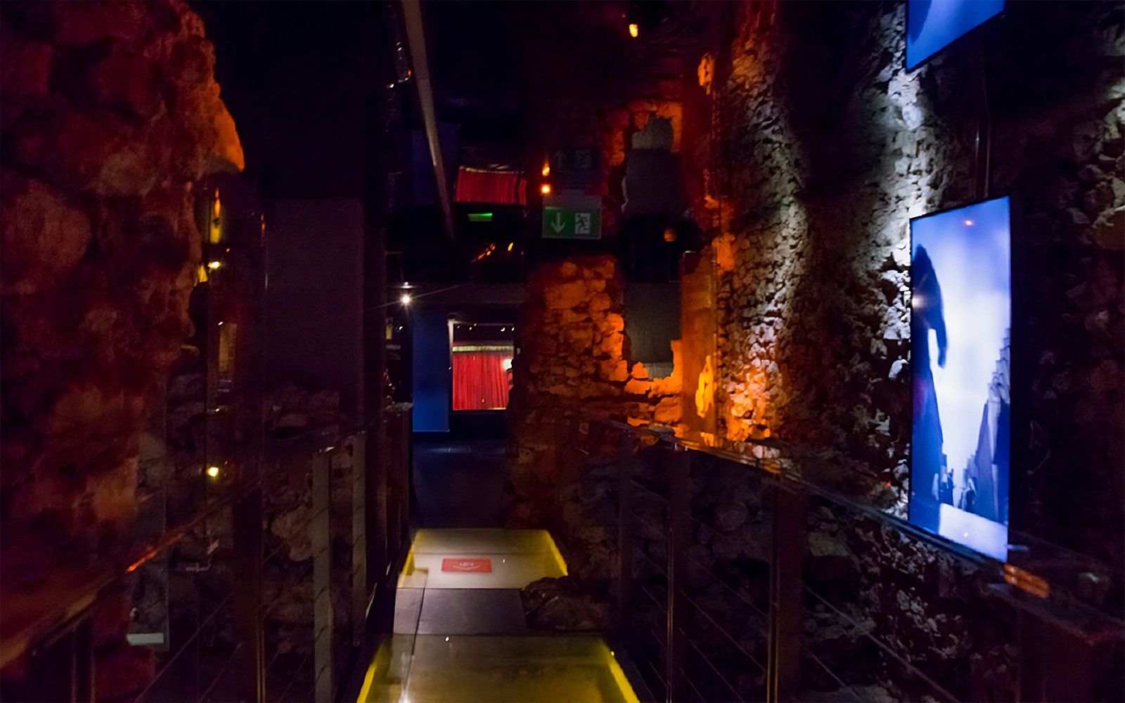 Gangur Rynek Underground safnsins með upplýstum steinveggjum í Kraká.