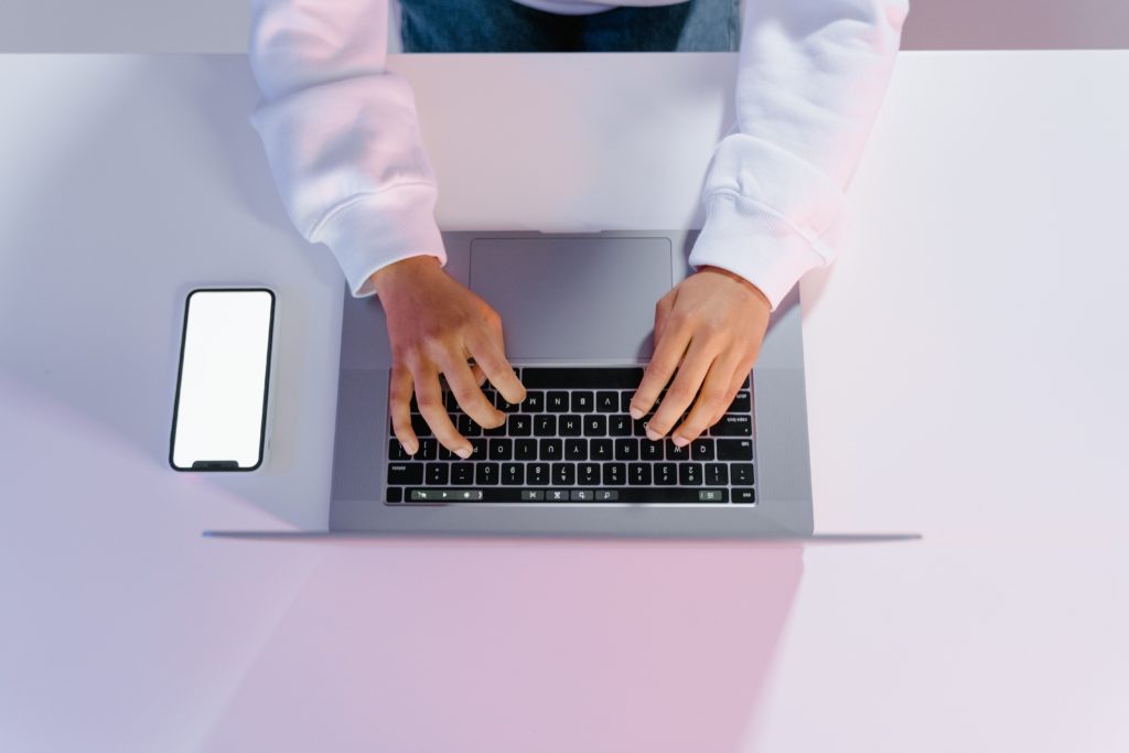laptop and phone on table as person types using free equipment for deaf or hard of hearing employees
