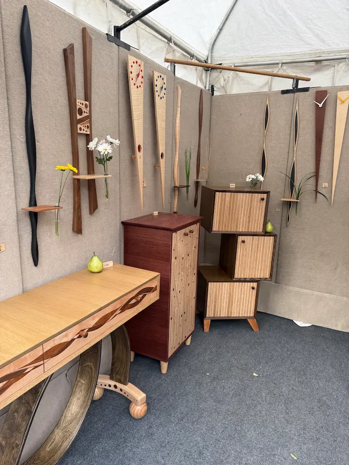 Handcrafted wooden furniture and wall art displayed inside an artist booth at Artisphere in downtown Greenville, featuring modern natural wood designs and minimalist decor.