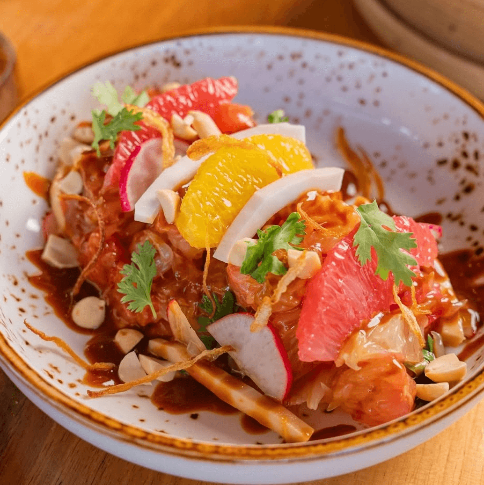 Vegetarian salad bowl with citrus, radish, herbs, and nuts.