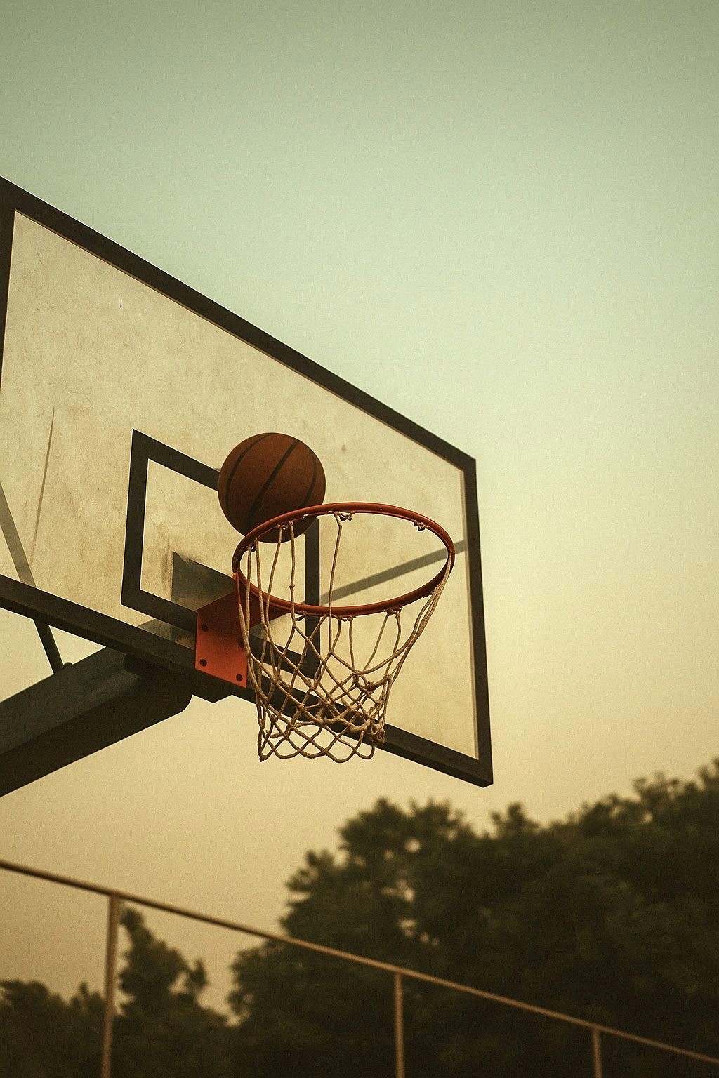 Ein Basketball fliegt im Freien in Richtung eines Korbes.