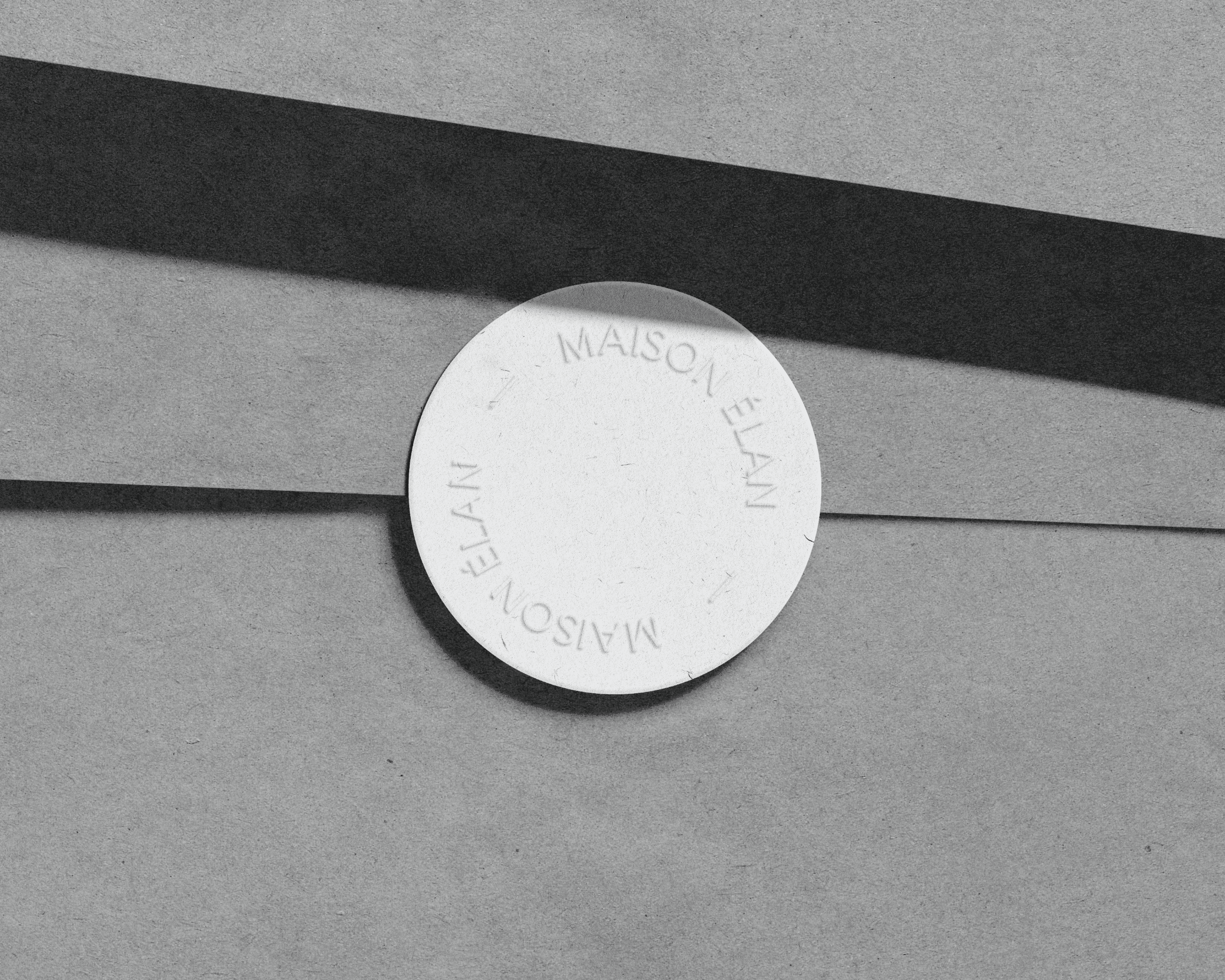 A round sticker with the Maison Élan logo design embossed on it.