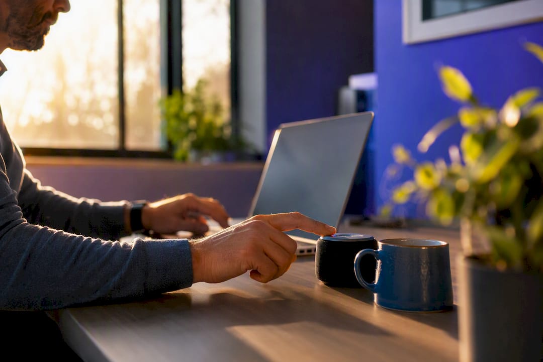 Hands placing smart voice device on desk