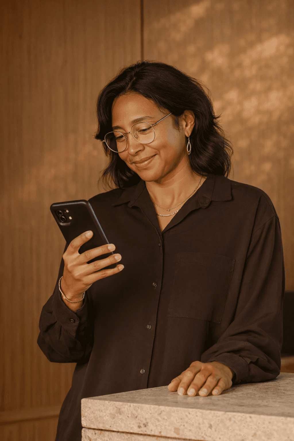 Woman looking at a smartphone while leaning on a stone counter