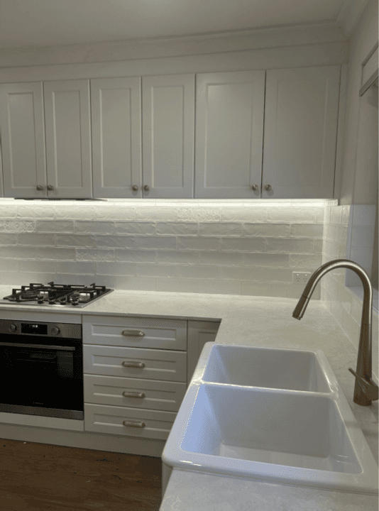 Sparkling white kitchen with gas cooktop and double sink after a residential clean in Perth