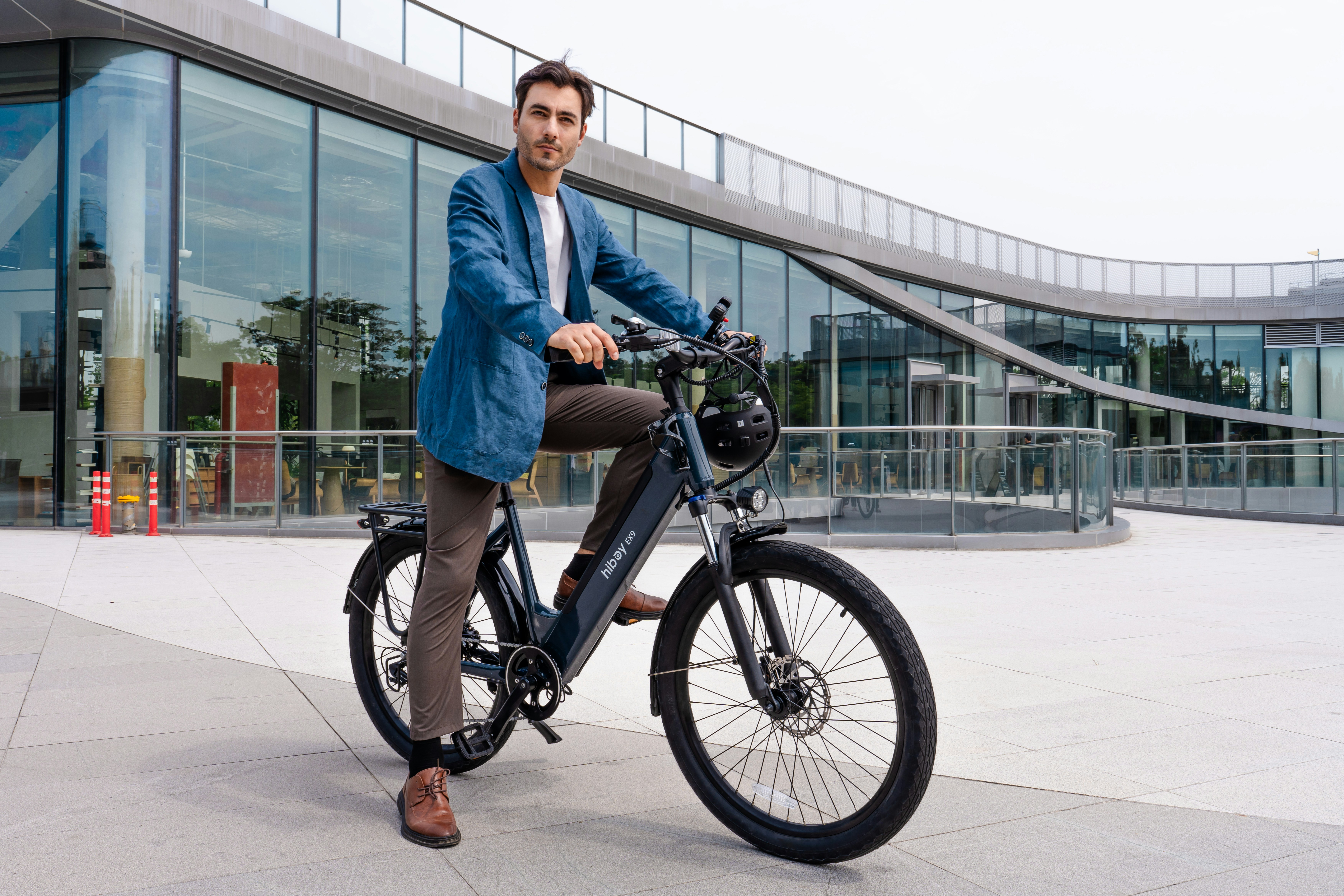 Man in blue jacket riding electric bicycle outdoors.