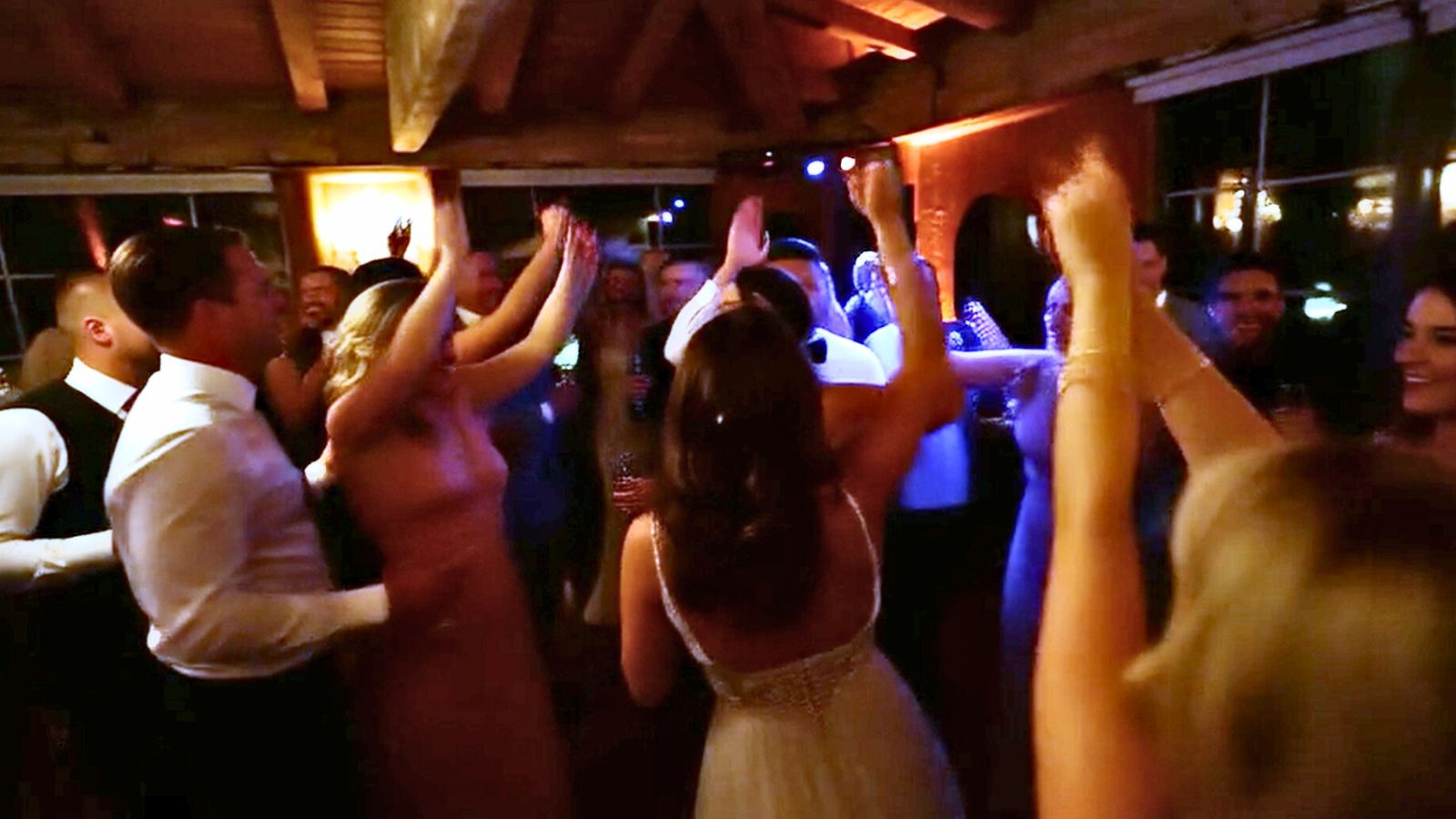 Guests dancing together on a wedding reception dance floor, smiling and celebrating the newlyweds.