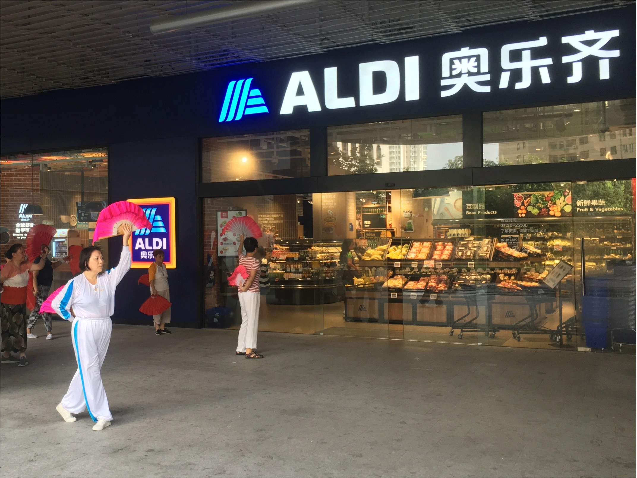 Woman in Shanghai practices fan-work out the front of Aldi supermarket