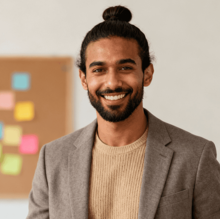 A smiling man with a bun hairstyle, showcasing a cheerful expression and casual attire.