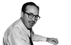 A black and white photo of a man with glasses and a mustache sitting at a desk, smiling while working with a typewriter. In front of him are typed papers, possibly a screenplay or script, hinting at a professional writing or screenwriting setting.