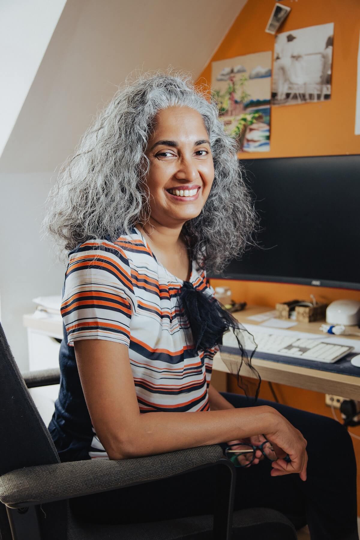 photo of Jennifer George in her work space looking towards the camera and smiling
