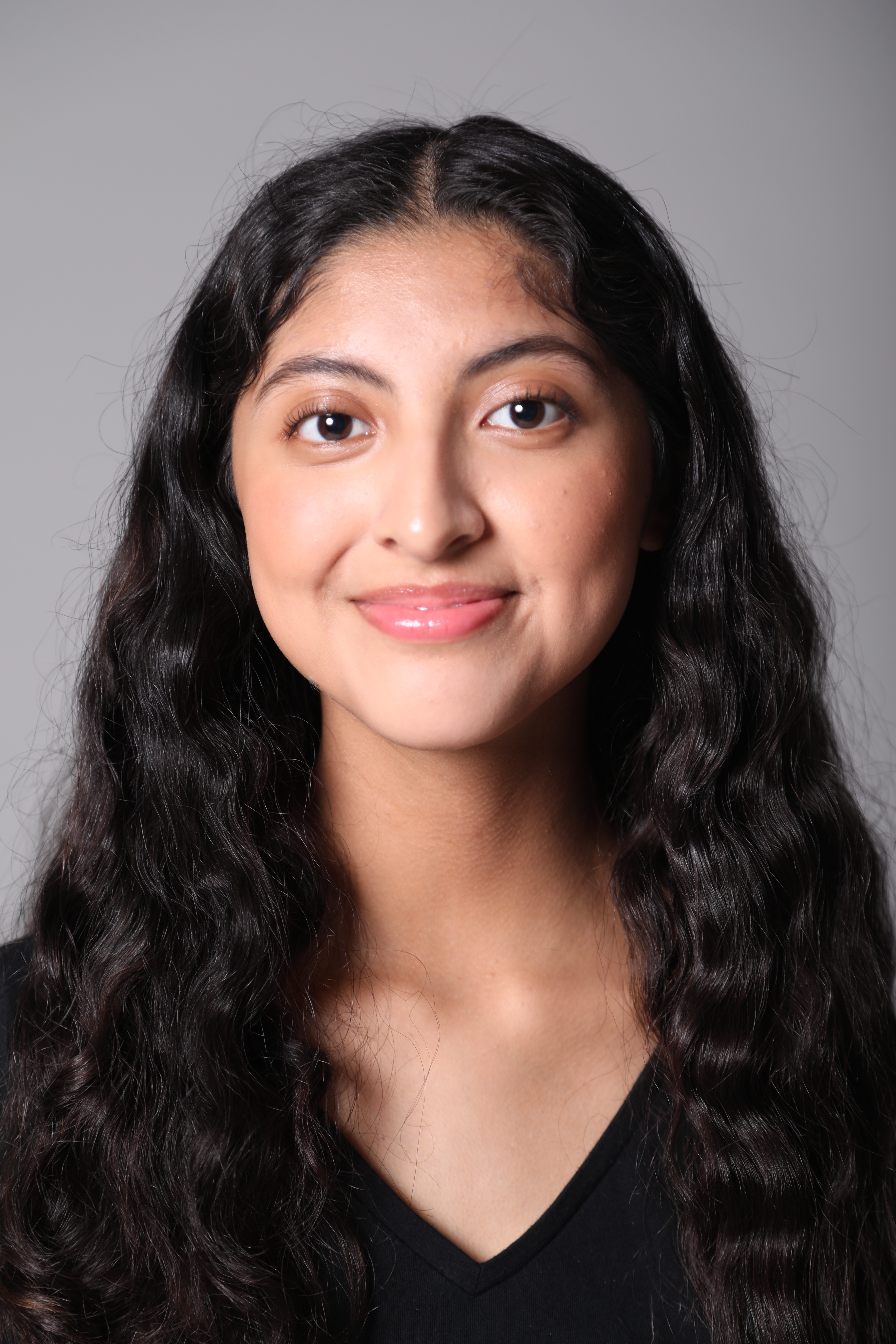 A thoughtful young person with dark hair gazes to the side, captured in soft black and white lighting.