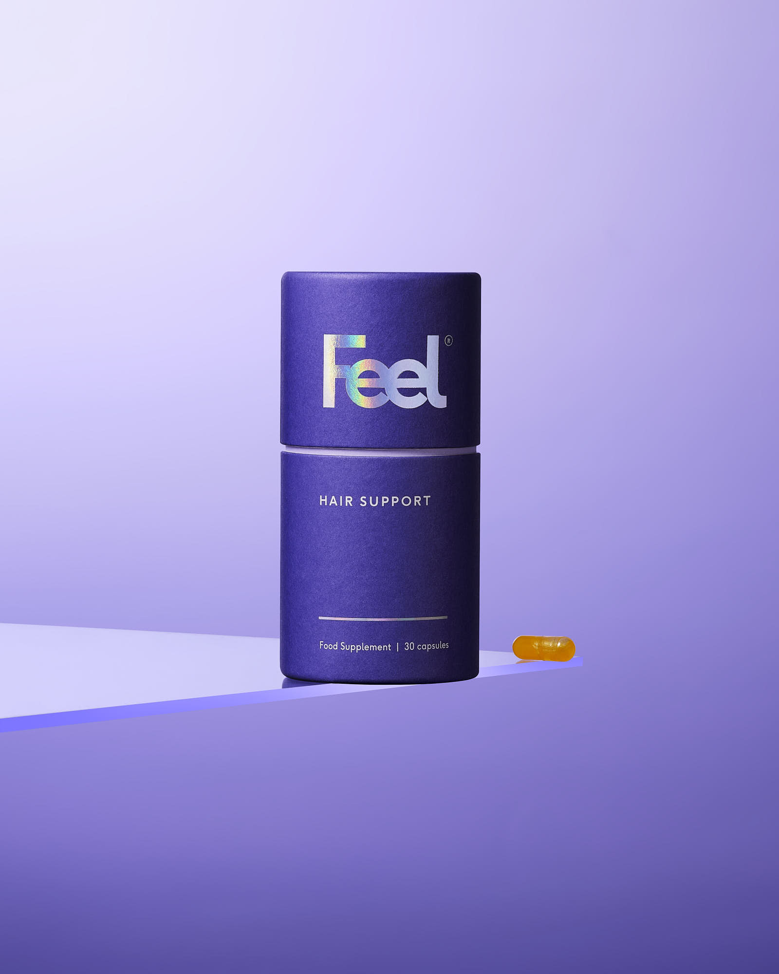 A purple cylindrical container labeled "f" with a capsule beside it, set against a soft purple background.