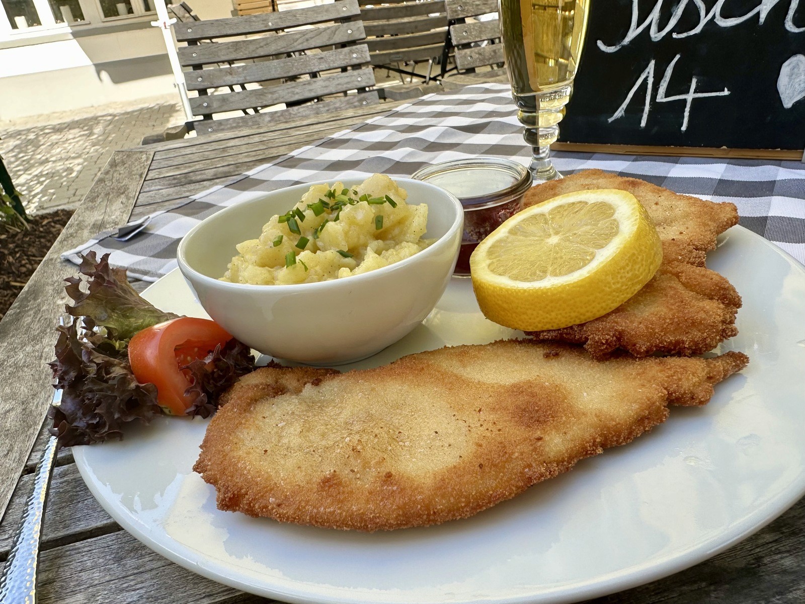 Schnitzel with lemon and potato salad served at an outdoor table.