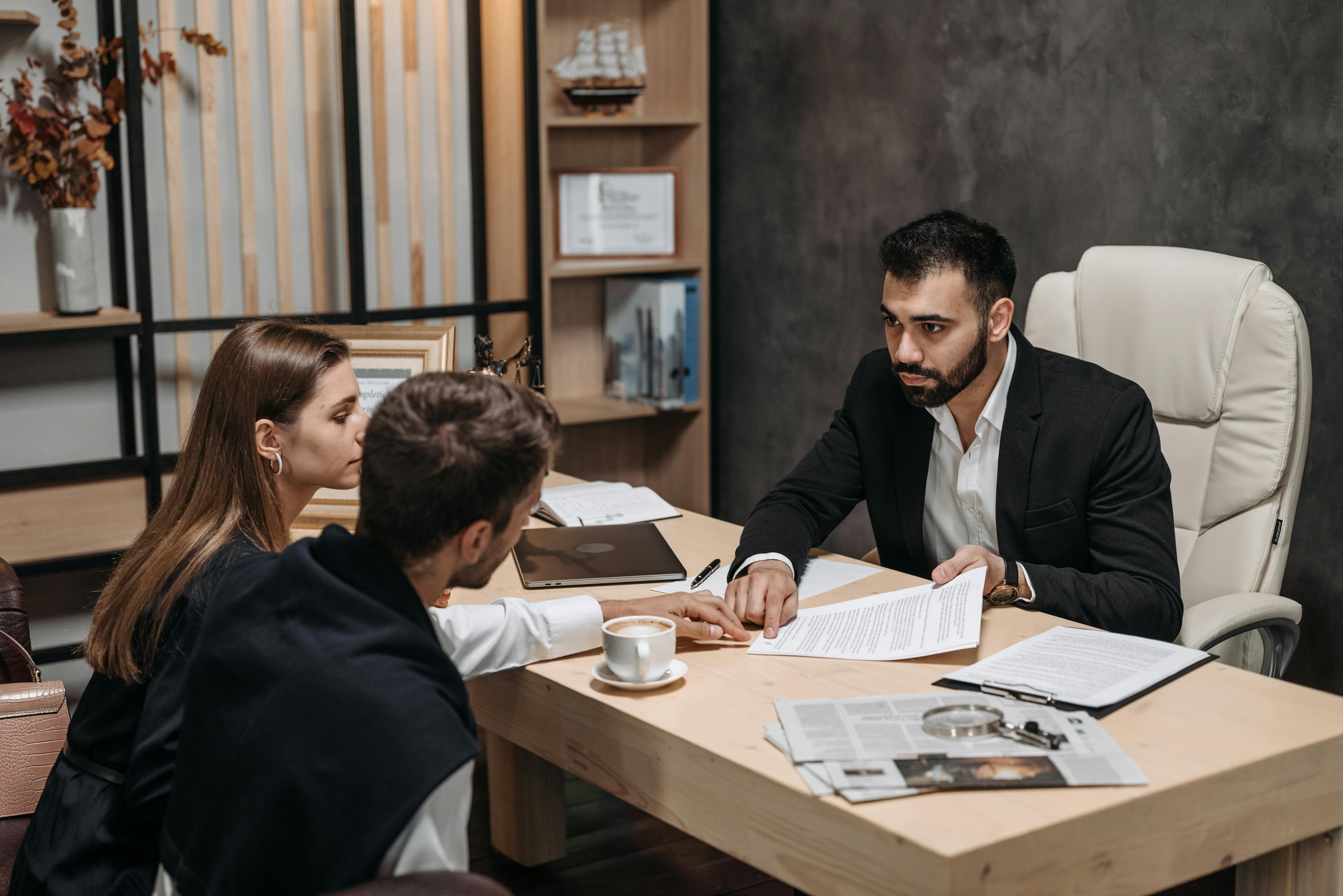 Business professional reviewing documents with two clients during a consultation meeting