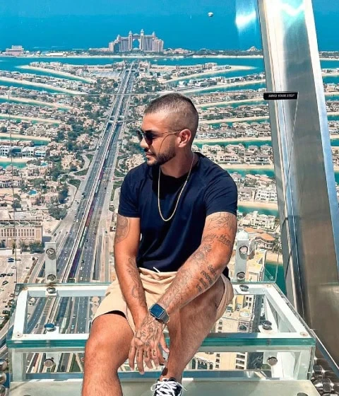 henrique está sentado em uma estrutura alta, com vista para uma paisagem urbana de Dubai