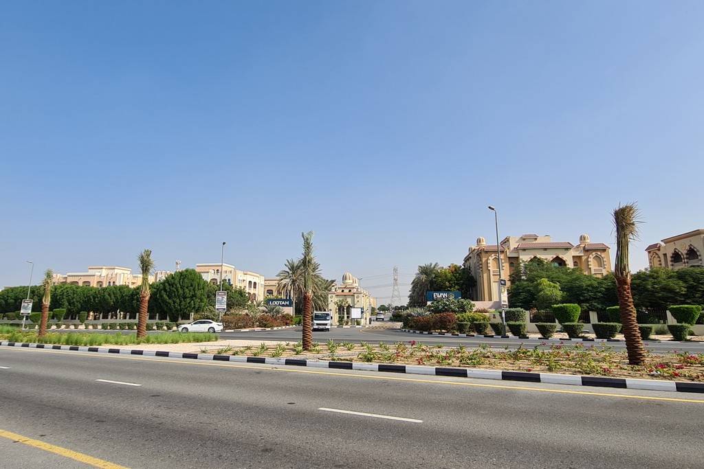 A parking lot at Ewan Residence filled with various parked cars under a clear blue sky.