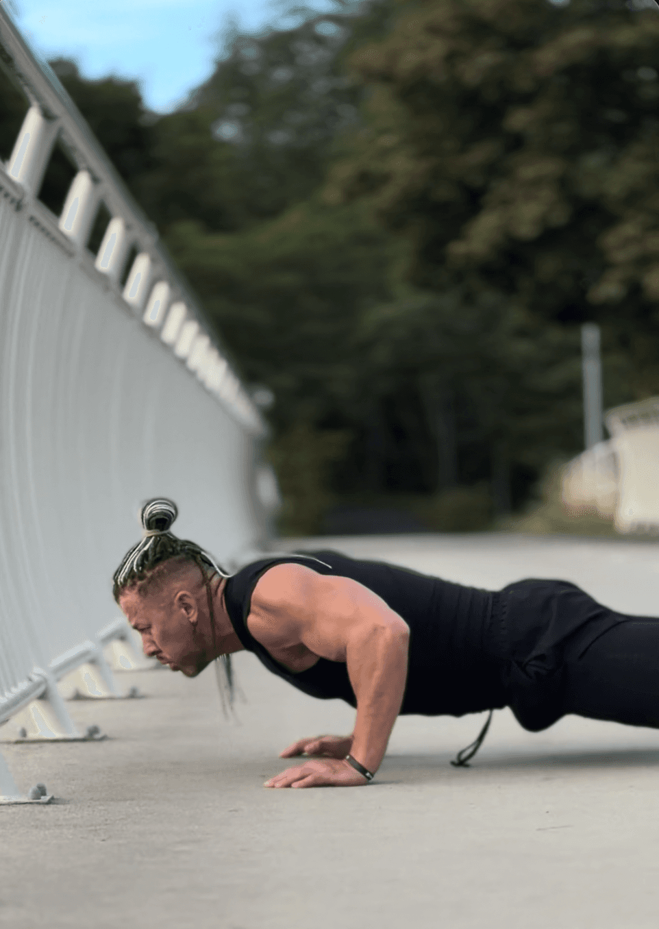 Gespierde man voert push sled-oefening uit in een sportschool, omgeven door gewichtsschijven en fitnessapparatuur.