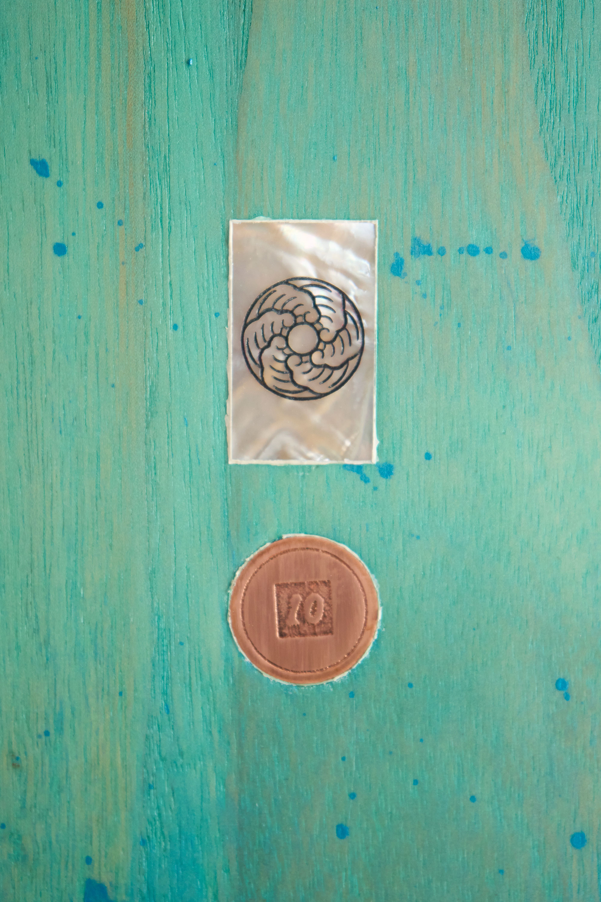 Mother of pearl and copper inlays on a wooden surfboard deck