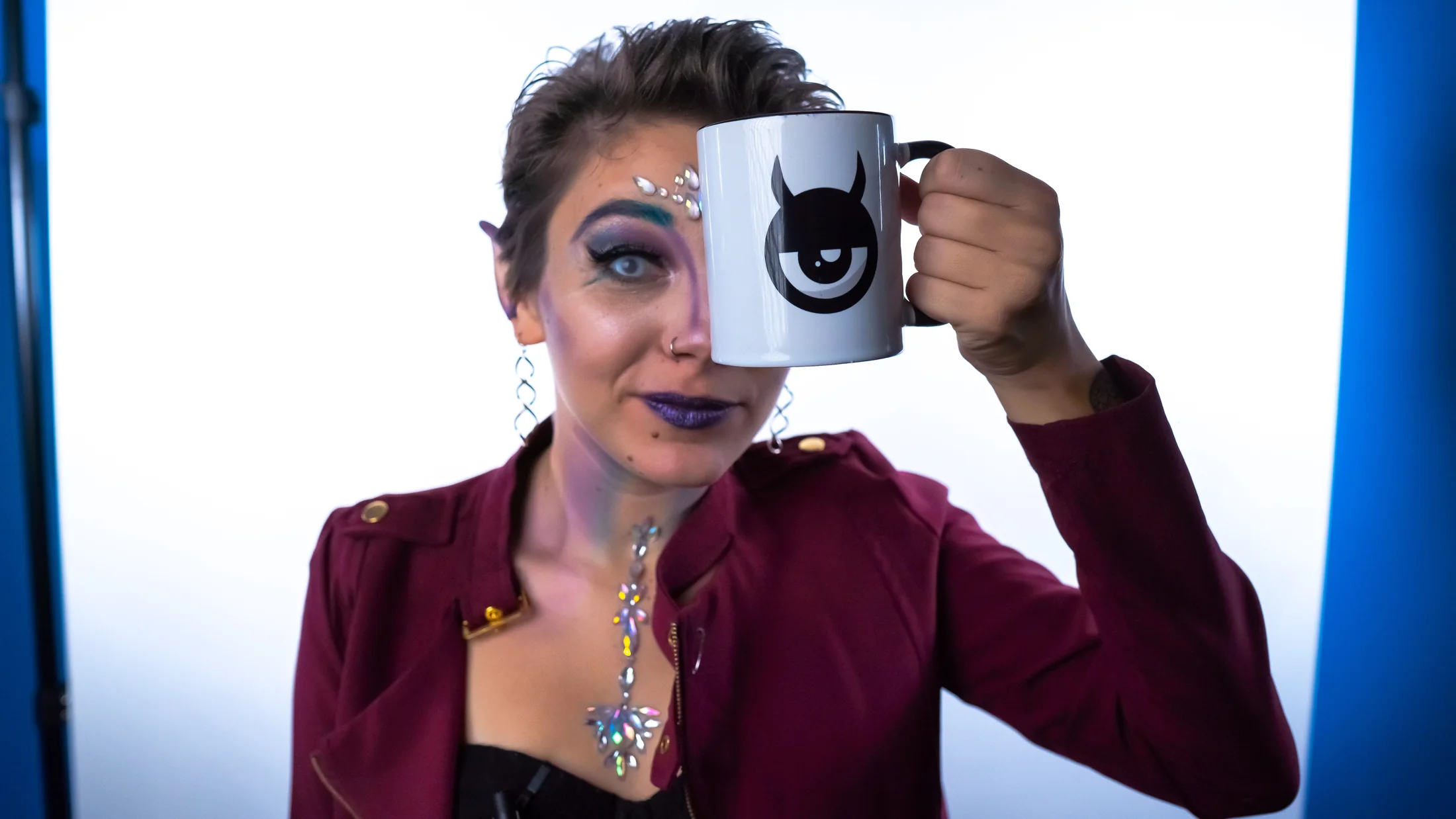 Avery Mako holding a mug with the Desk/Show brandmark