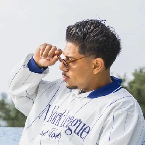 Side profile of a man adjusting his sunglasses in a white jersey like tee