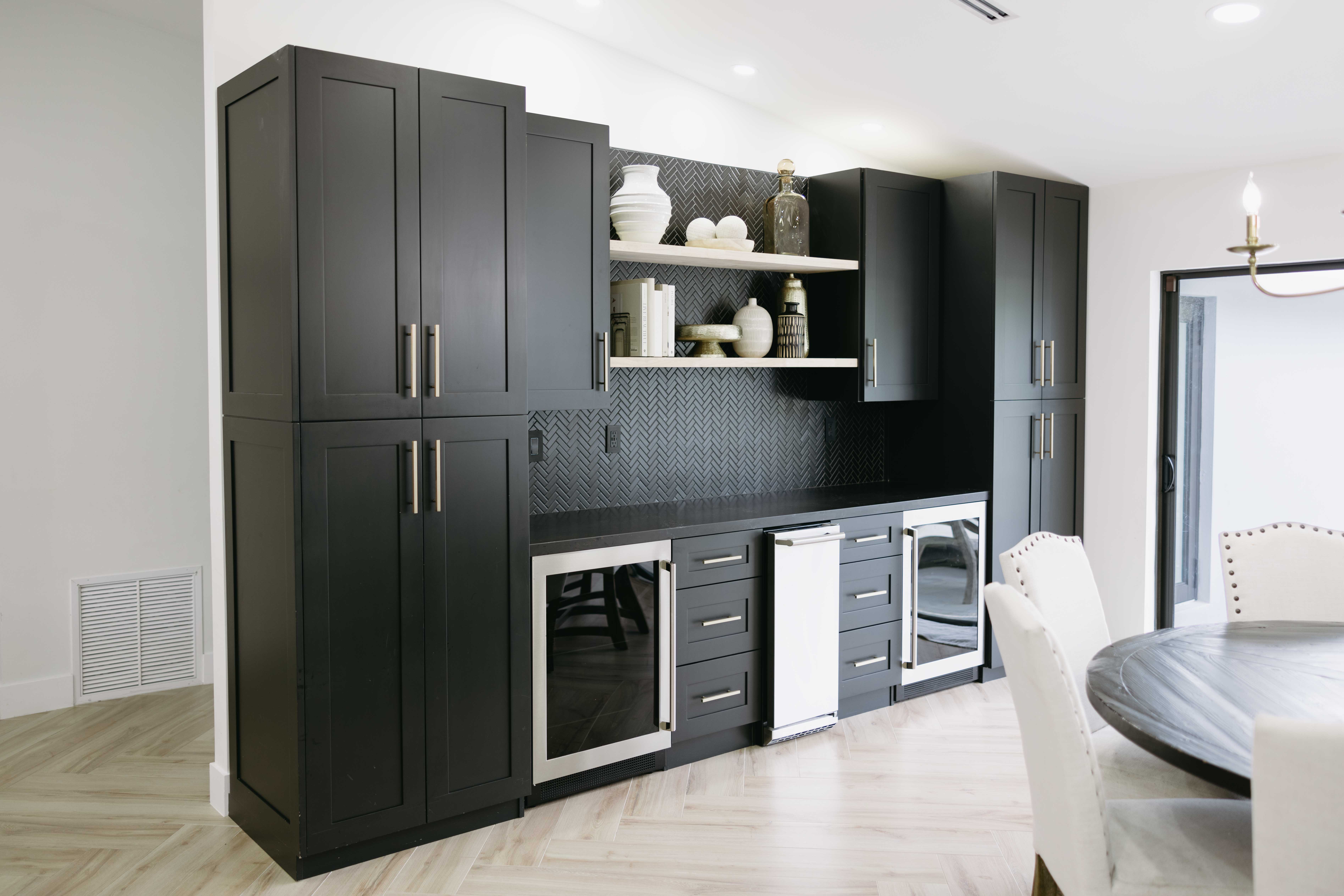 Modern dark gray kitchen island with built-in wine fridges and shelving.