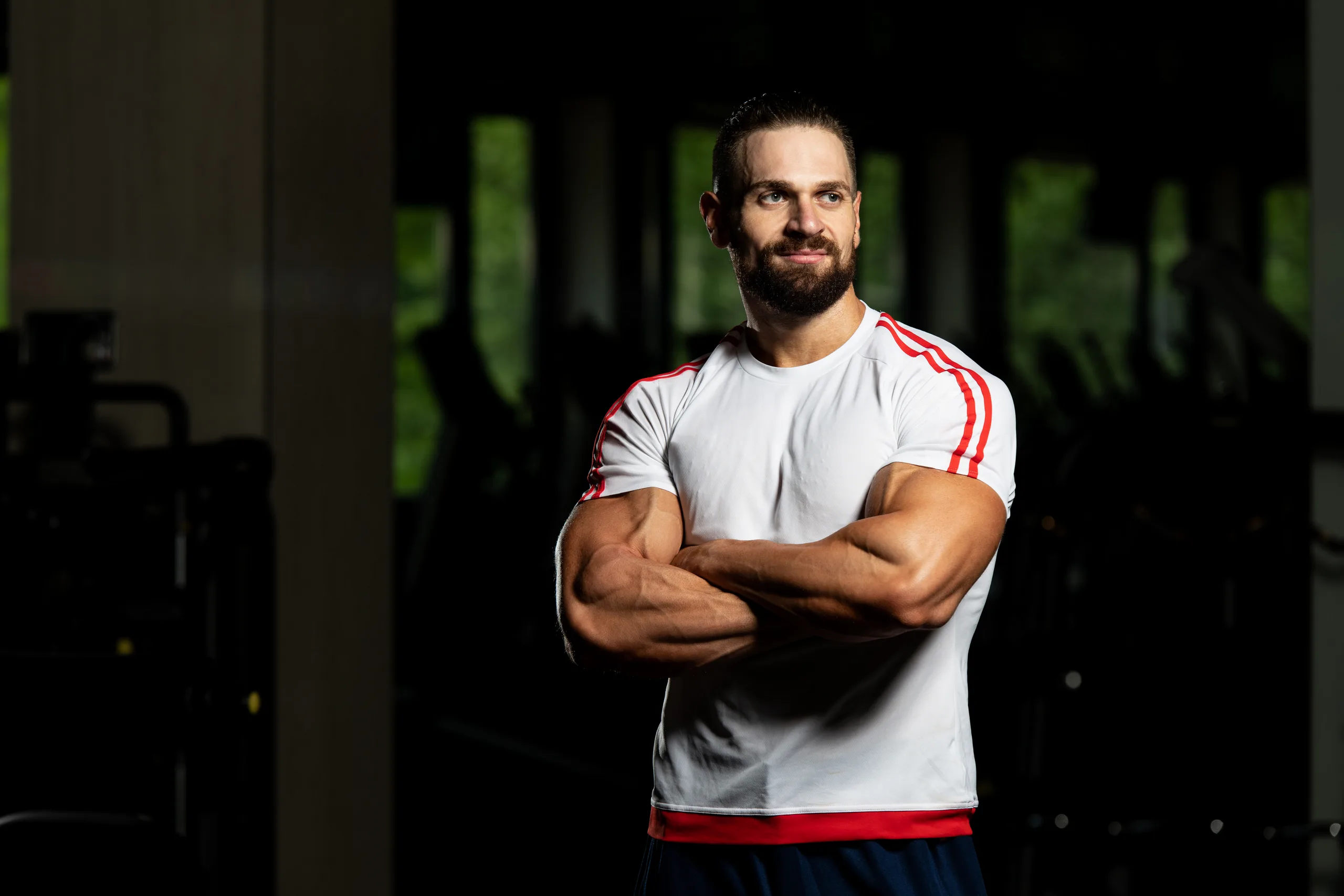 homem com braços cruzados em pose confiante na academia