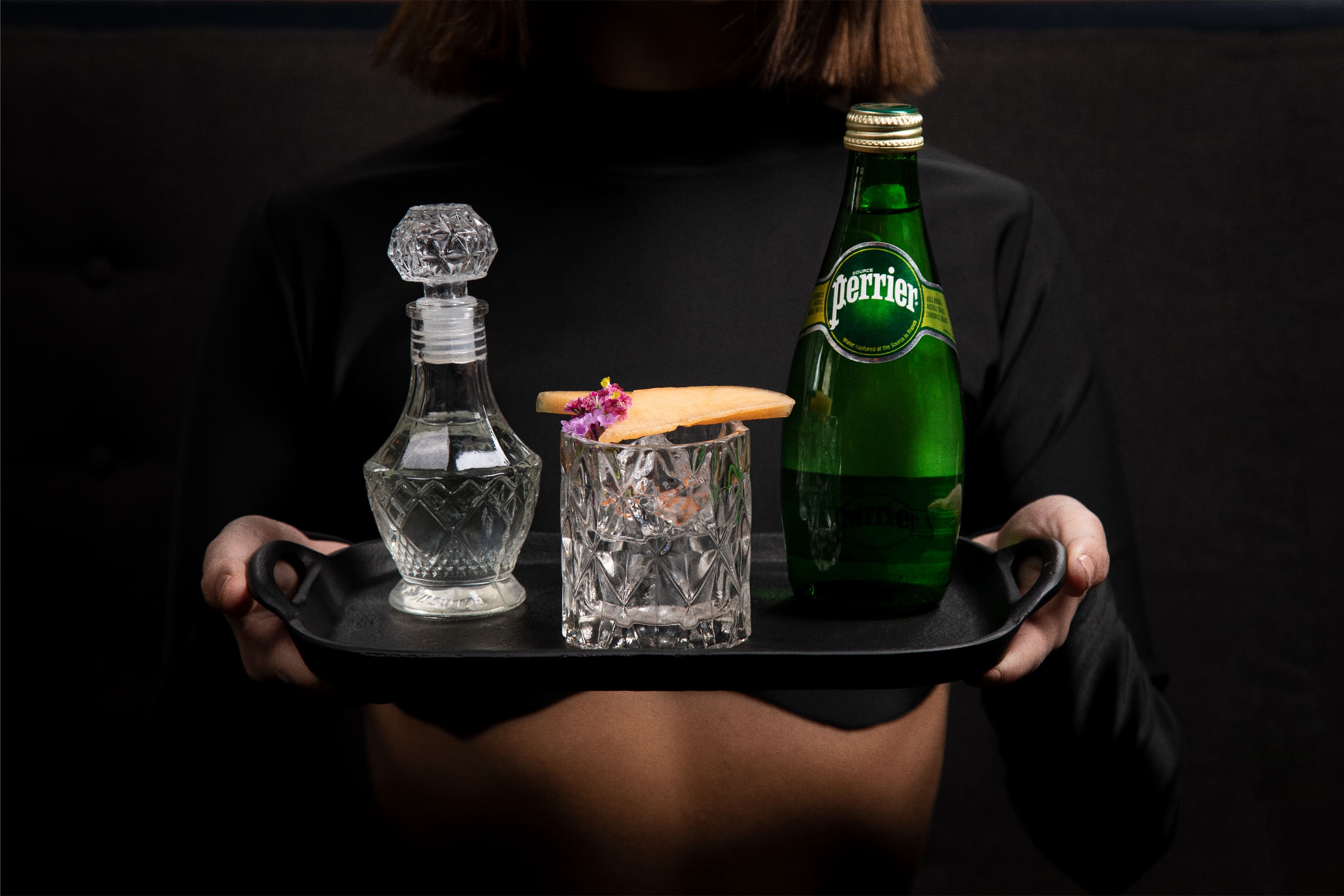 perrier bottle and cocktail on a tray