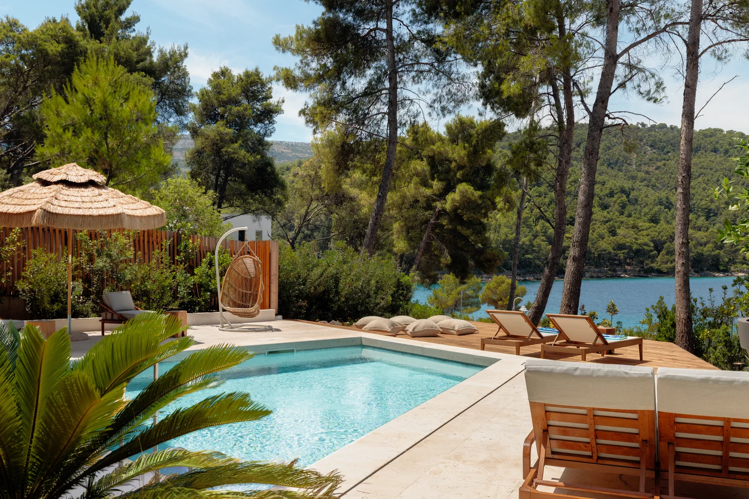nfinity pool blending into the ocean view, minimalist sun loungers in soft neutral fabric, curved architecture
