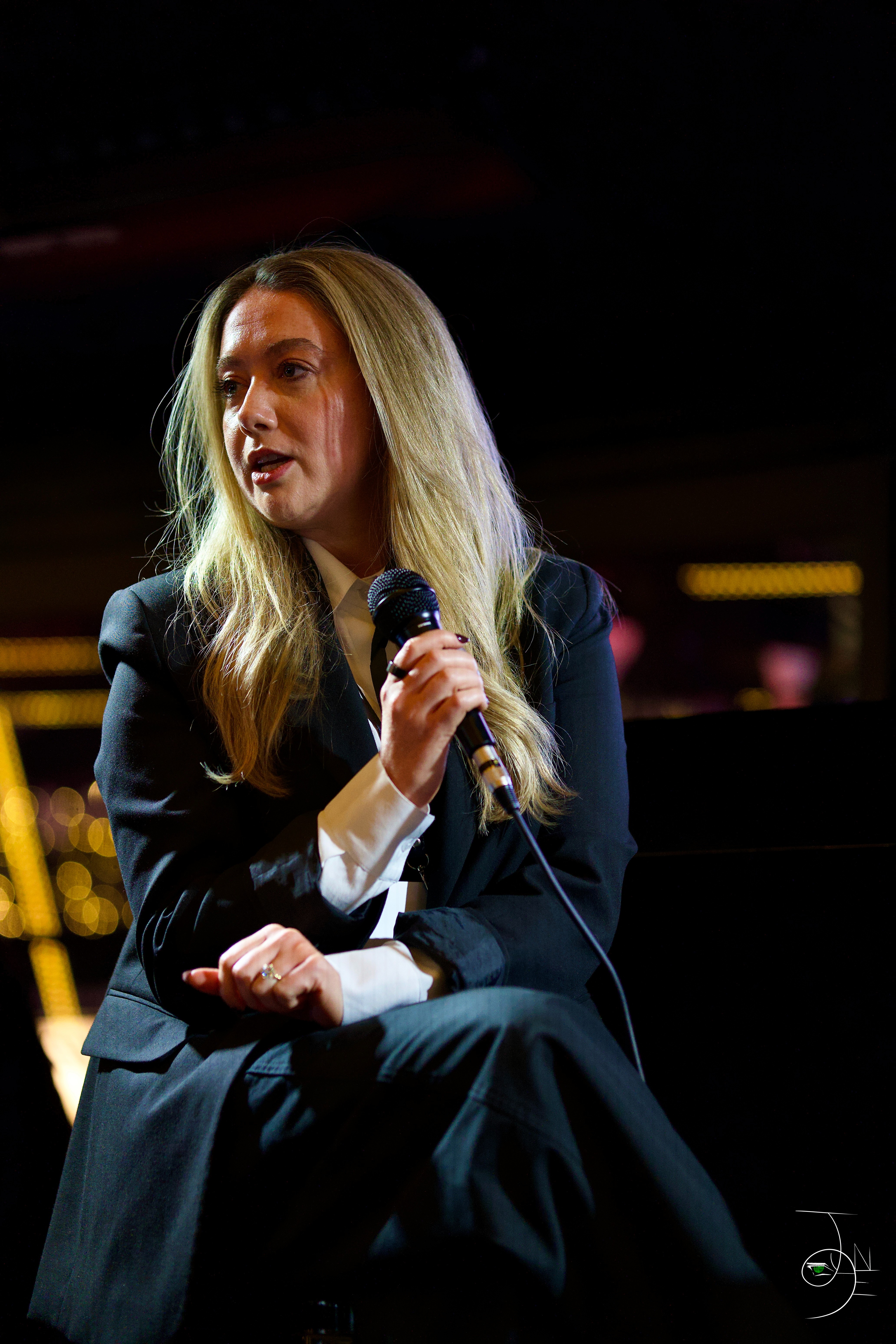 person discussing while standing in front of a large screen in front of people inside dim-lighted room