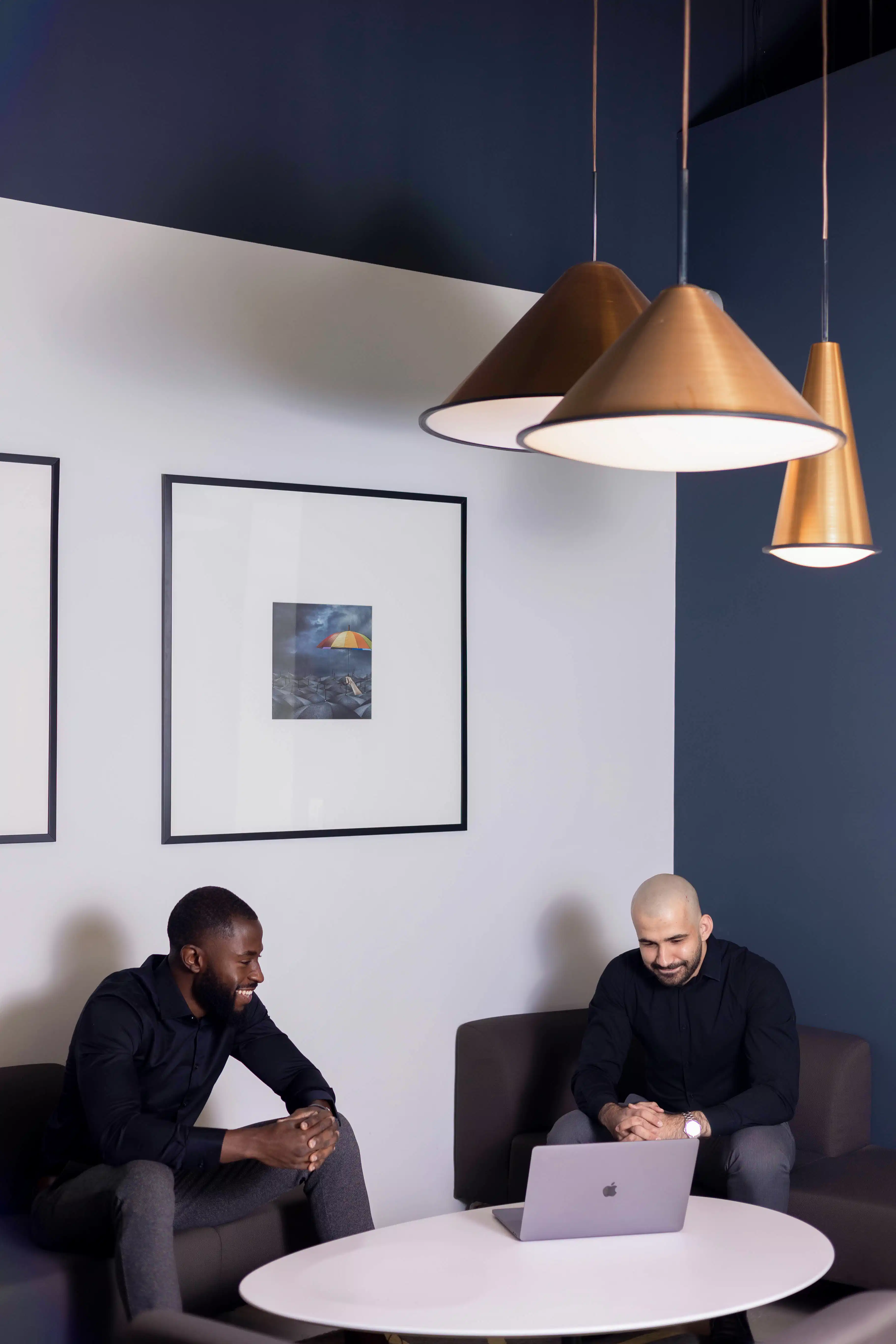Close-up portrait of a person wearing a gray insulated hooded jacket with the hood up, showing their face framed by the hood against a light background.