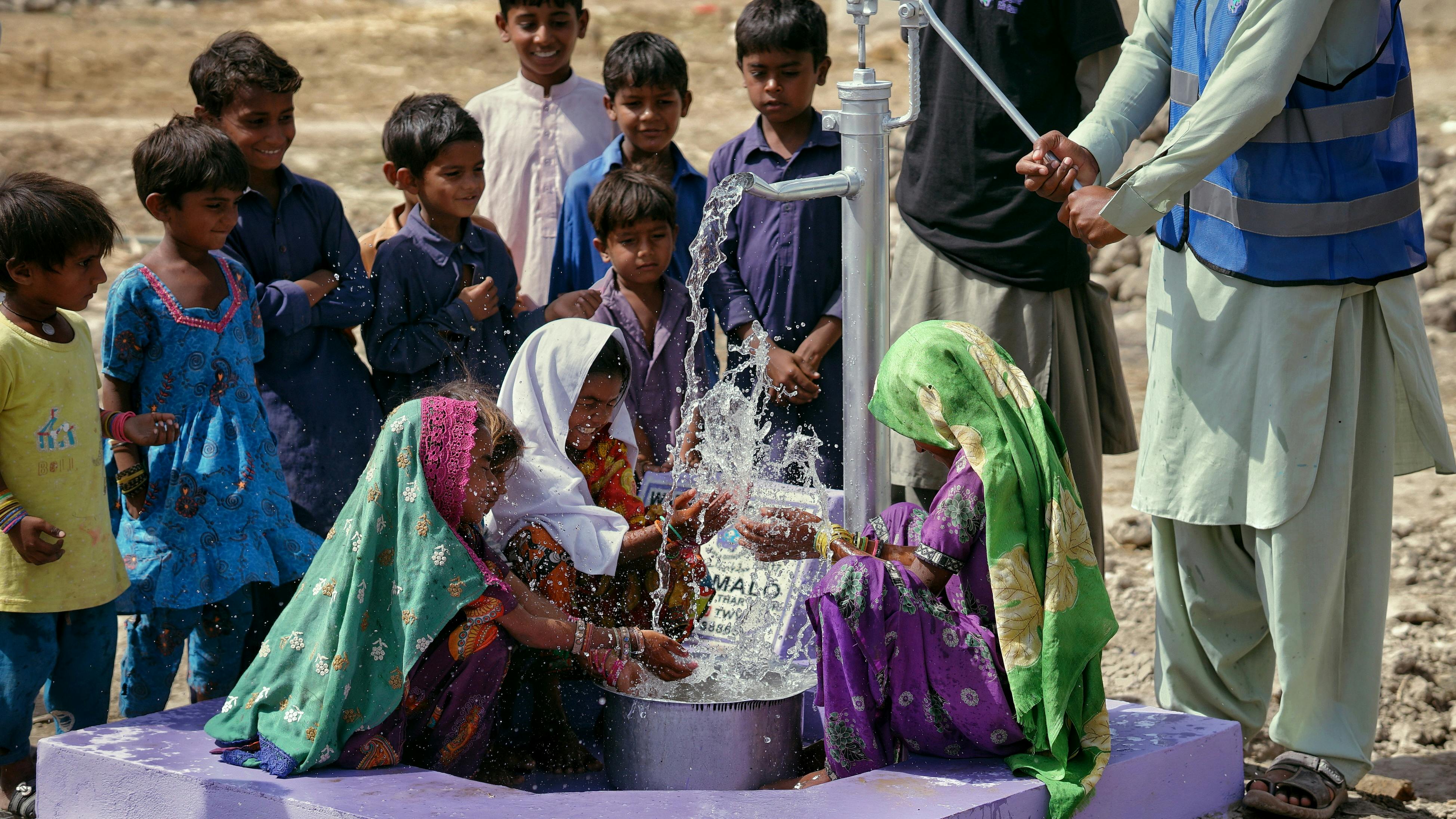 Indian women and children splashing in new well built by a 503c nonprofit.