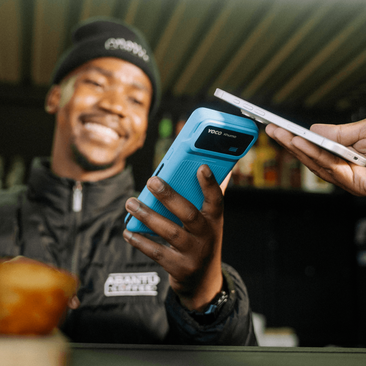 A man holds a Khumo 2 point of sale to receive a smartphone payment