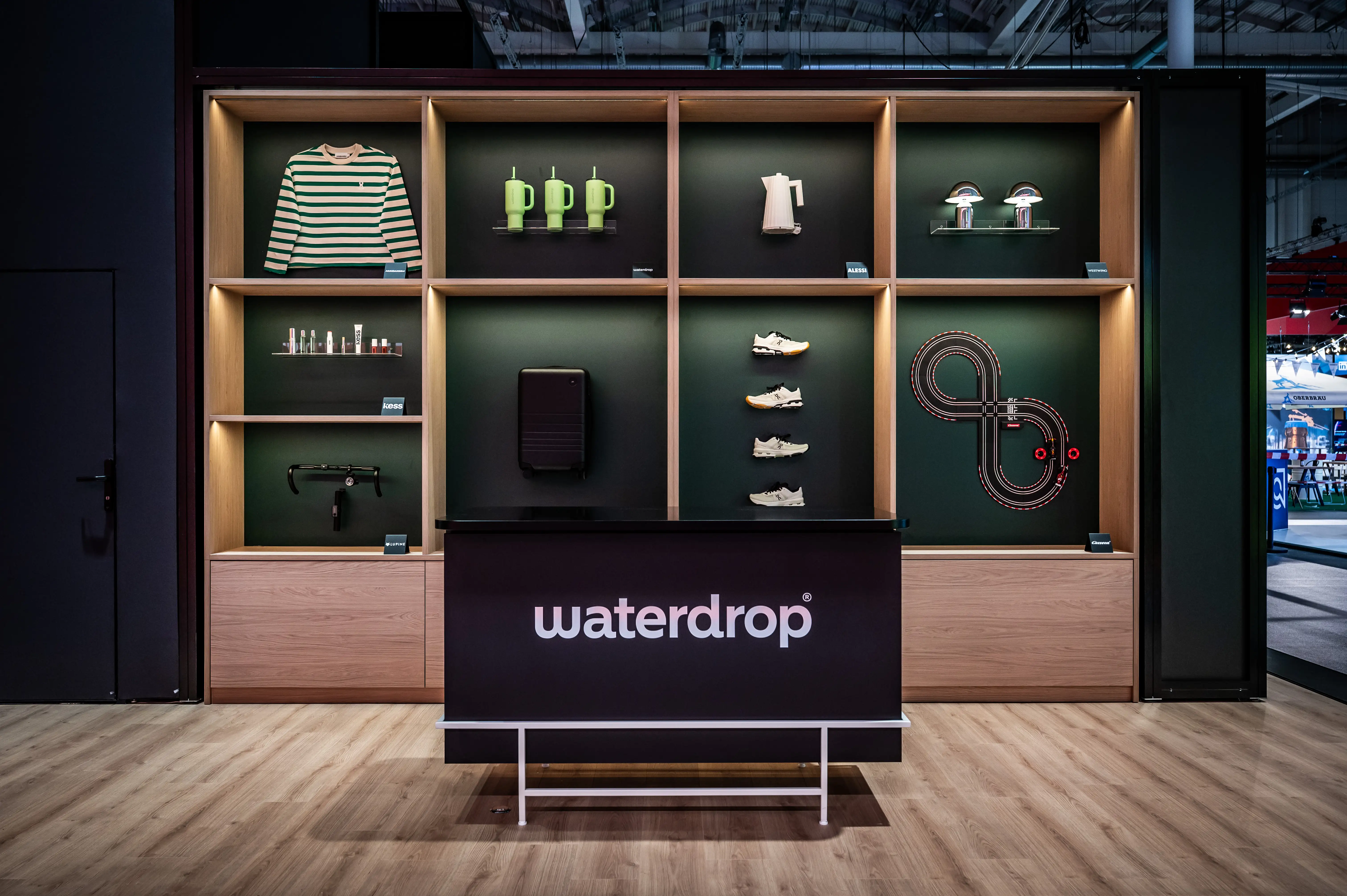 Waterdrop counter in front of a wooden shelf wall with merchandise products in green niches.