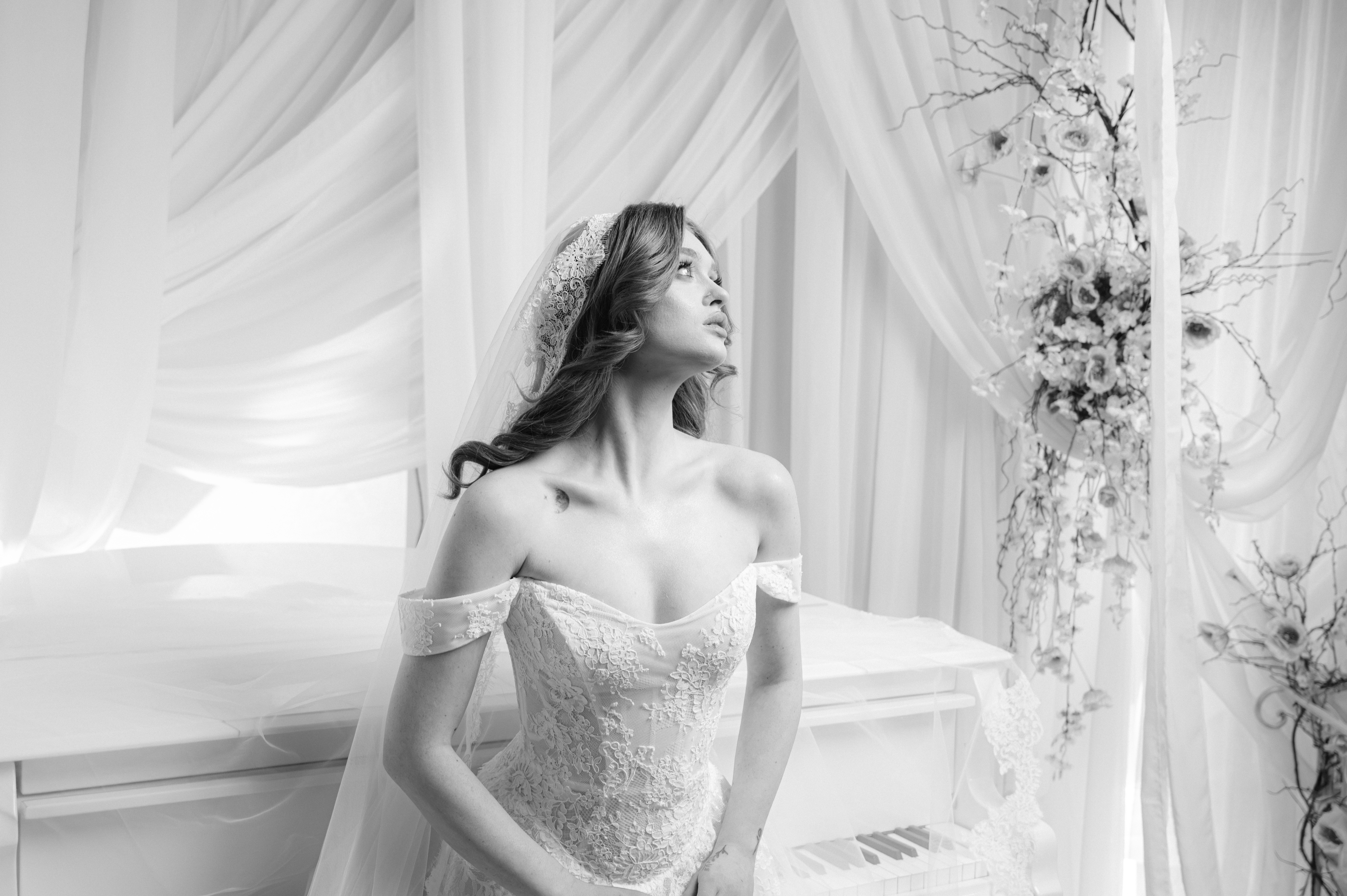 Mireasă fotografiată pe un pian alb într-un decor elegant și romantic, fotografie de nuntă în București