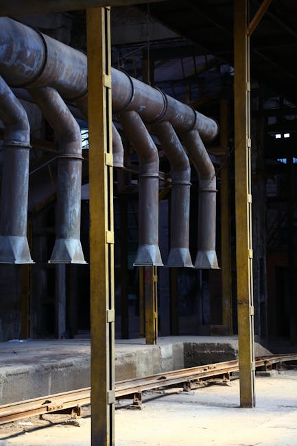 A view of industrial pipes and machinery inside an old factory setting.