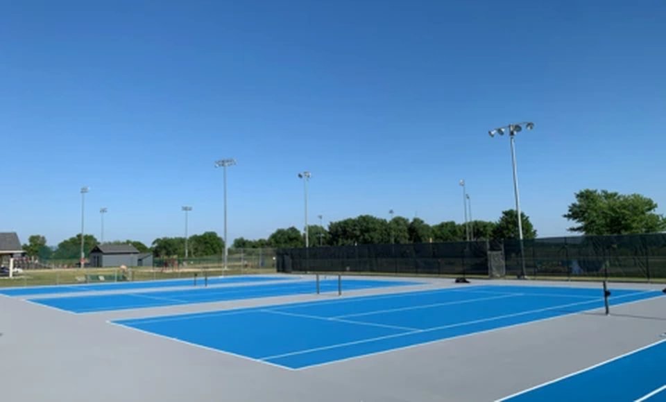 Renovated blue tennis courts at a country club facility with fresh surfacing and line striping.