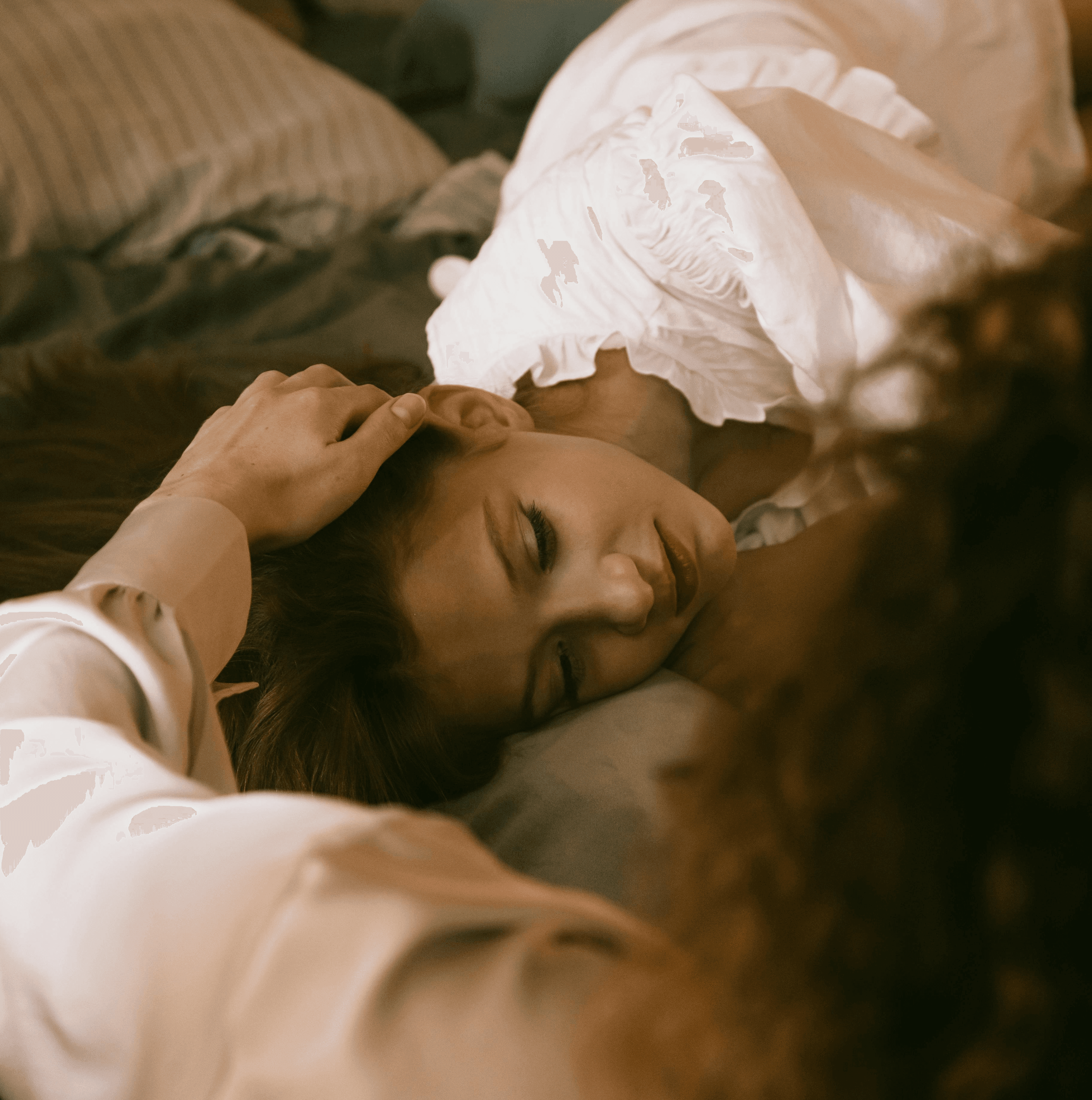 A client lies on a pillow while a therapist gently strokes her head to comfort her.