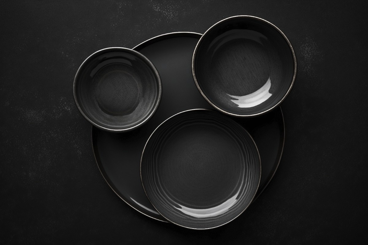 A modern house with large windows and a flat roof, surrounded by greenery against a clear blue sky.