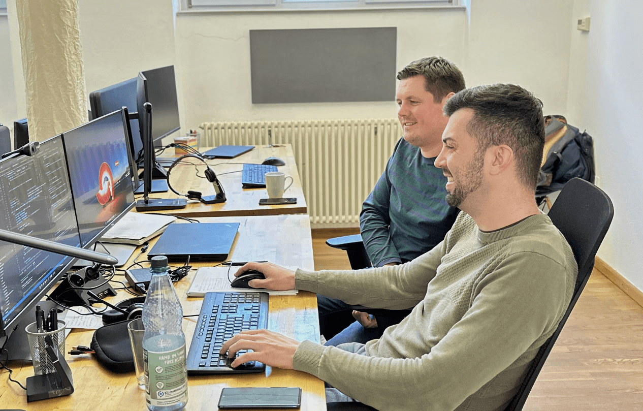 People laughing while sitting on chairs in front of computers