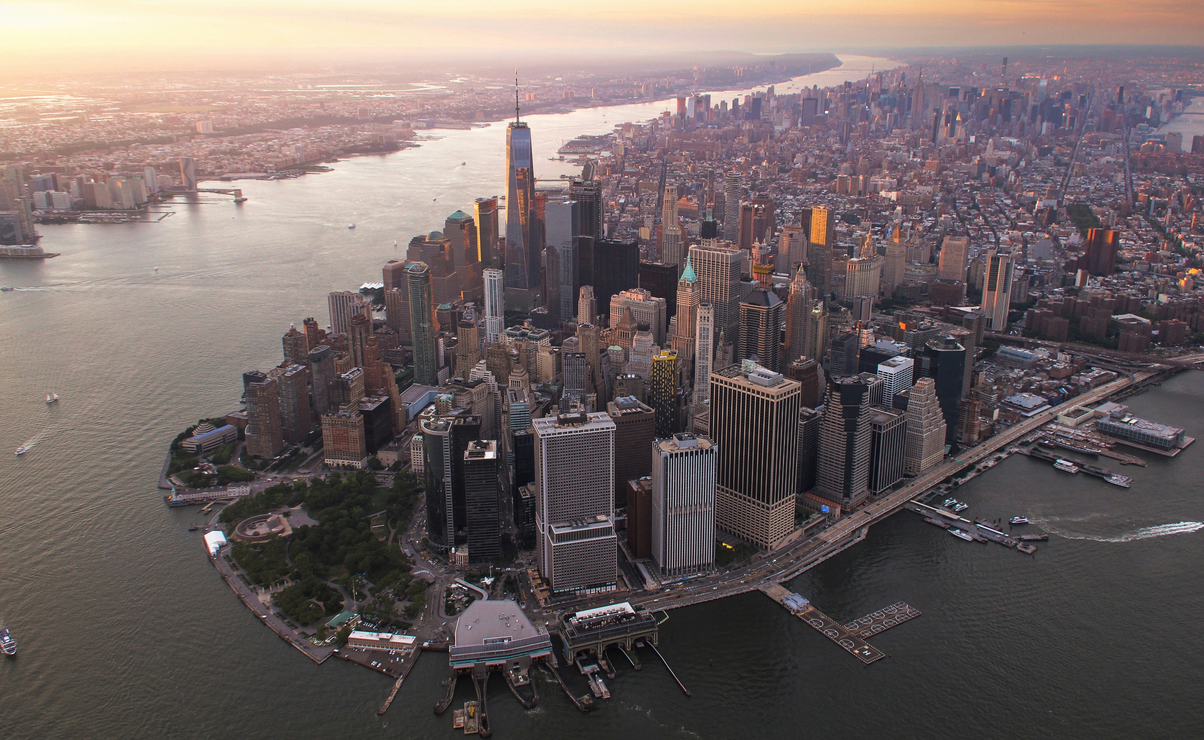 Aerial view of a bustling city skyline at sunset, featuring tall buildings and a river.