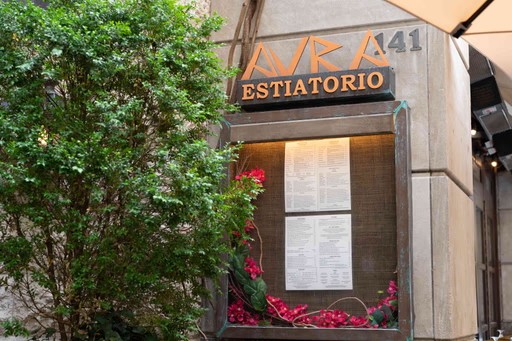 A close-up of a house exterior featuring a window with wooden shutters and a bush in the foreground.