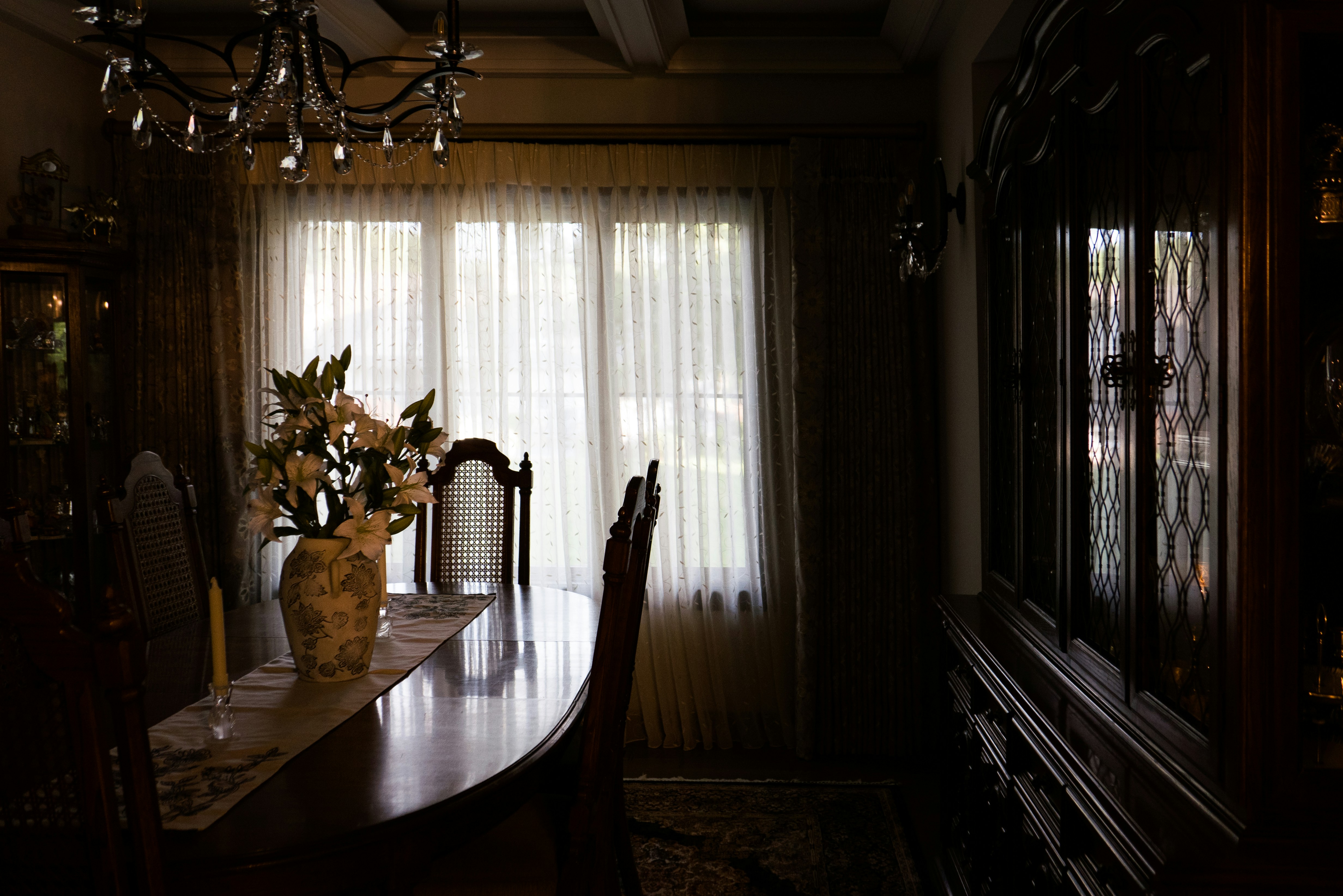 A traditional dining room illuminated by sunlight streaming through the windows.