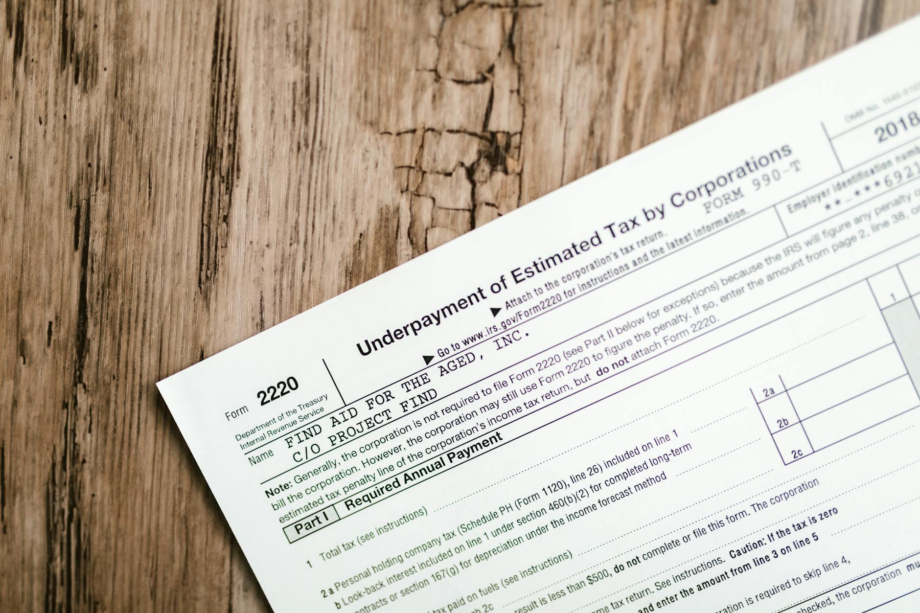 Paper tax form titled "Underpayment of Estimated Tax by Corporations" laid on a rough wooden surface