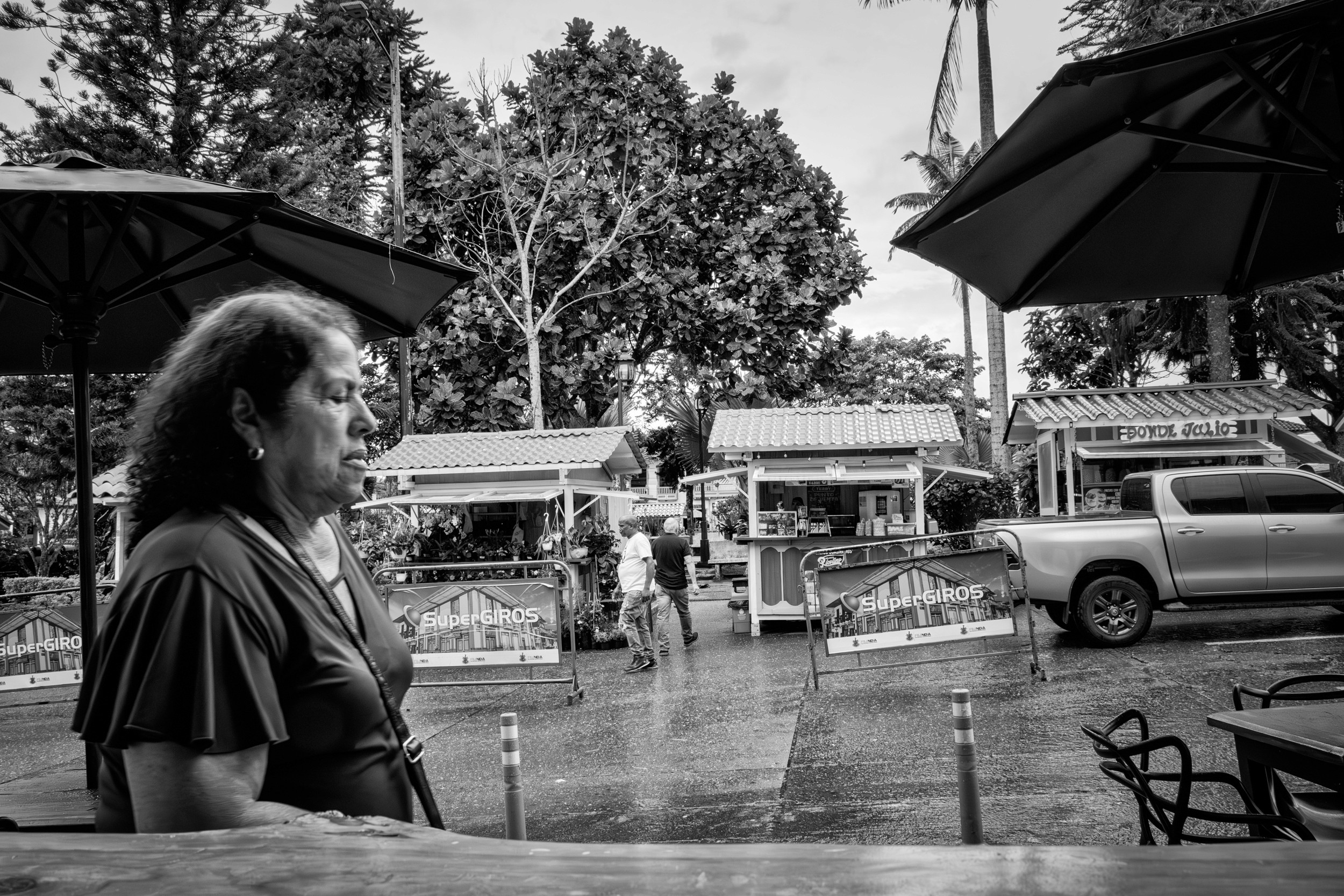 Rainy street scene with people passing by a bar window.